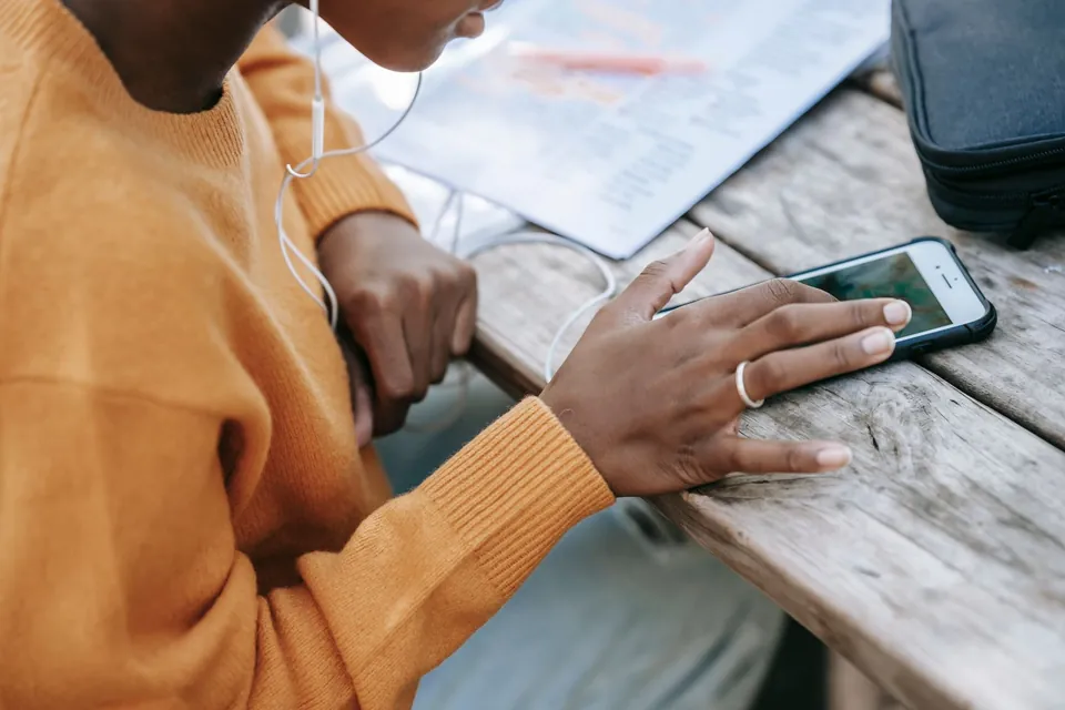 Hand resting on a smartphone lying flat on a wooden table before a flat-surface accelerometer check