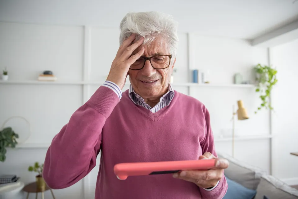 Puzzled man holding a tablet sideways while the screen refuses to rotate