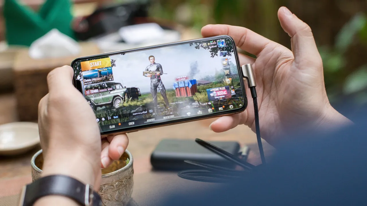Player holding a phone sideways with both hands during a mobile game that uses the accelerometer and gyroscope