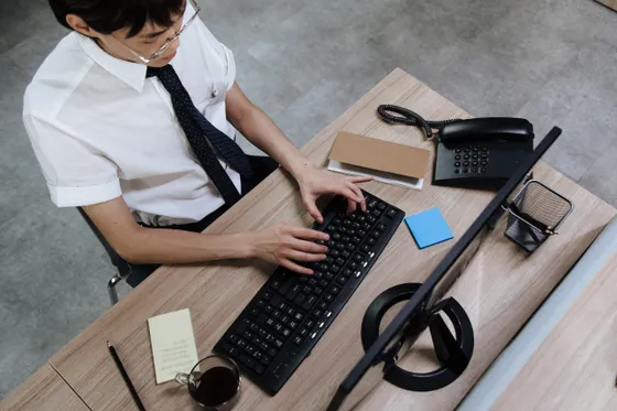 A person at a desk typing on a slim wireless keyboard, the setup where Bluetooth keyboard lag shows up most