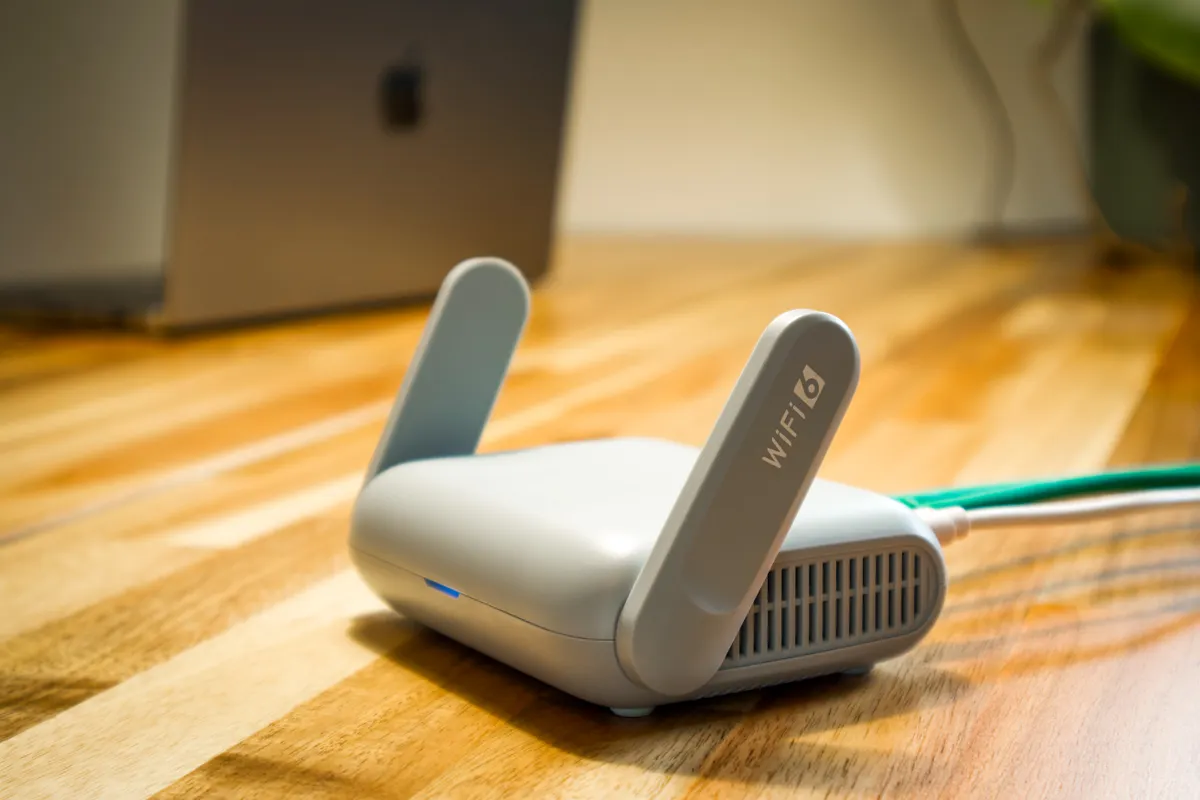 A Wi-Fi router on a desk next to a laptop, a common 2.4GHz interference source for Bluetooth keyboards