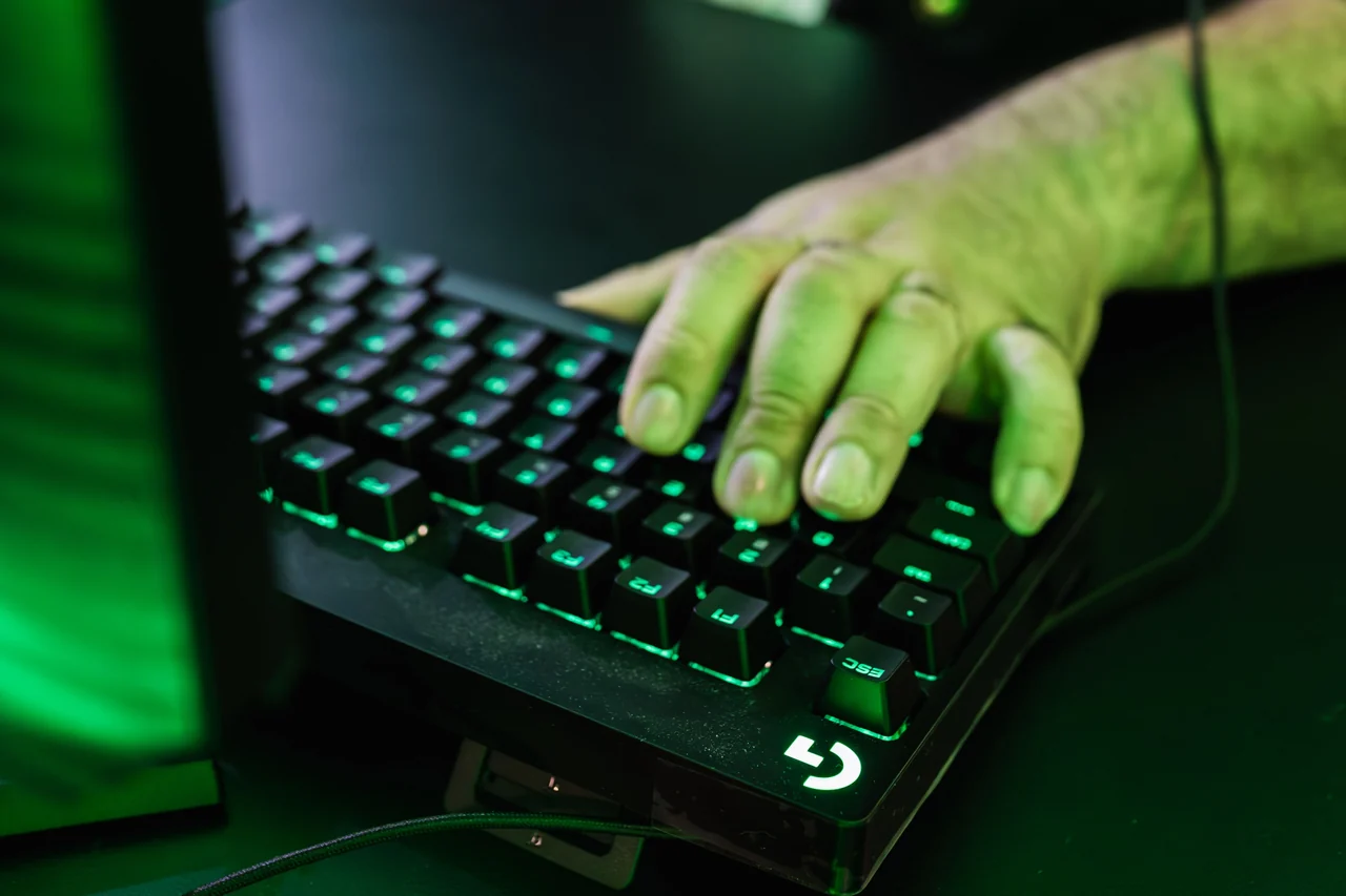 A player’s hand on a backlit keyboard during a computer game
