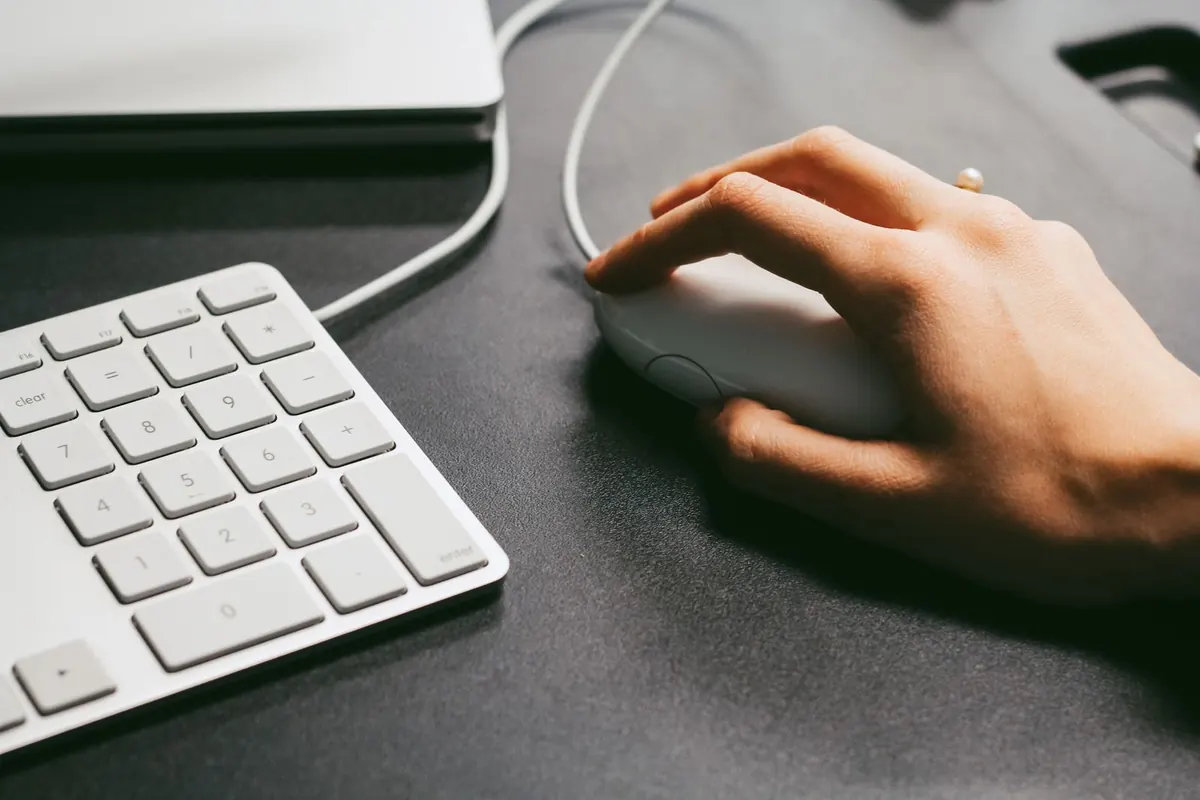 Hand moving a mouse across a dark desk mat to measure movement before changing DPI