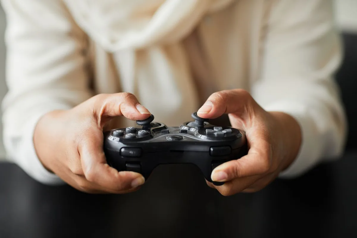 Close-up of thumbs resting on both analog sticks of a black gamepad, the area a deadzone monitors