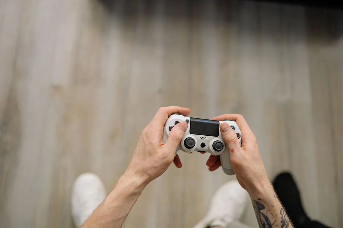 Top-down view of hands holding a white PlayStation controller while testing it over USB and Bluetooth