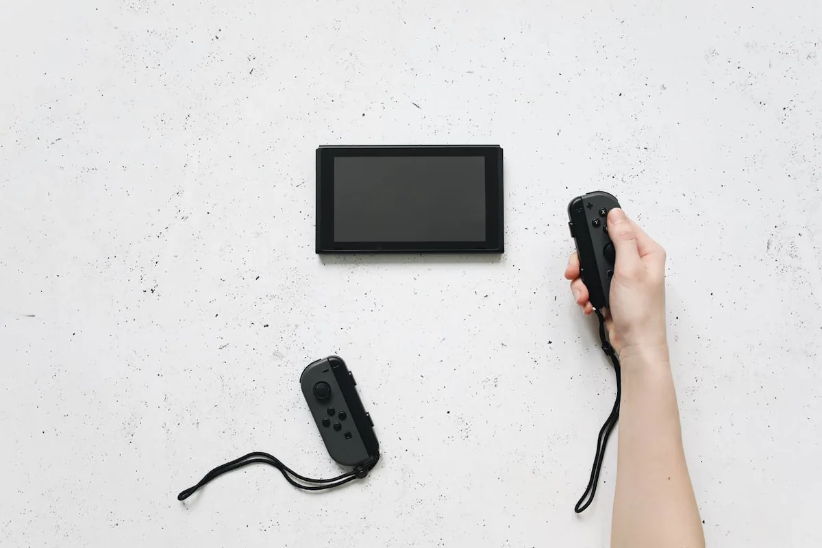 Nintendo Switch console with detached Joy-Con controllers, one held in hand