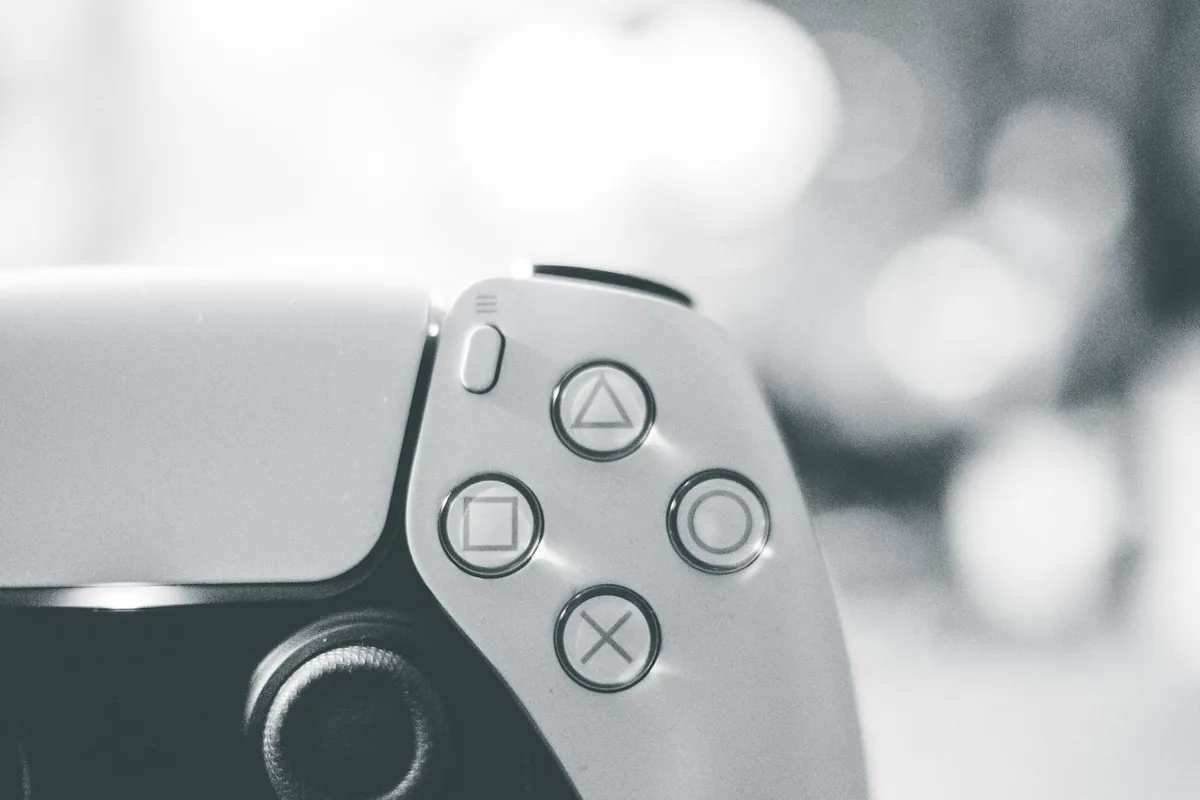 Close-up of a white PS5 DualSense controller showing the analog stick and face buttons