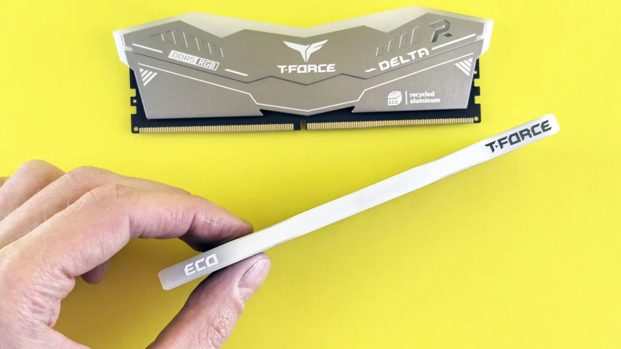 Hand holding a DDR5 memory module next to a second DDR5 RGB stick on a yellow background