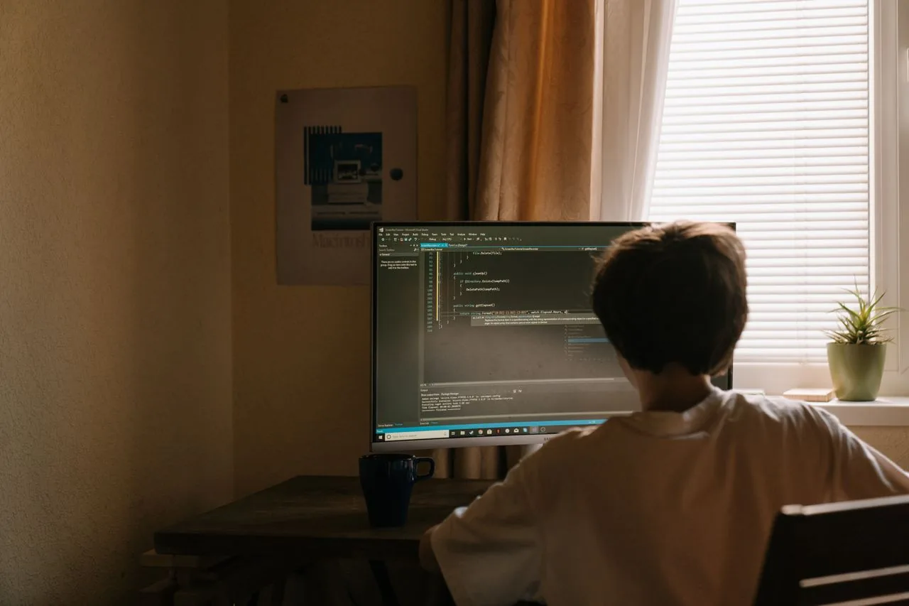 A person evaluating a monitor in a softly lit room from a normal seating distance, the realistic way to judge backlight bleed