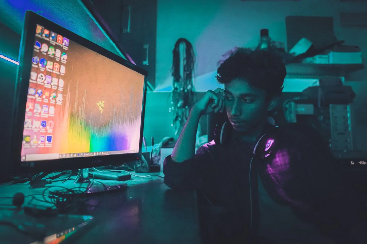 A person in a dim room looking closely at a glowing computer monitor to inspect it for backlight bleed and IPS glow