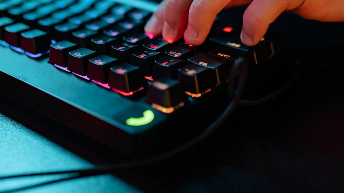 Nahaufnahme von Fingern, die Tasten einer RGB-Mechaniktastatur drücken