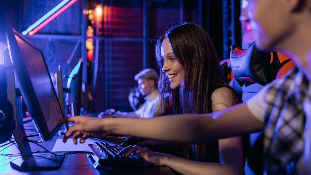 Gamer at a desktop PC setup playing a fast-paced game — the scenario where keyboard ghosting is most noticeable