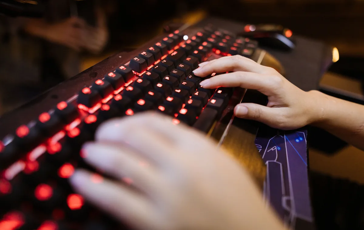 Hands typing on a backlit keyboard while checking key sound consistency