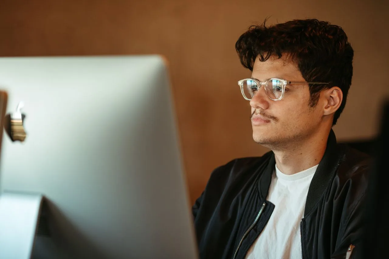 A person in glasses leaning in close to inspect a computer monitor for a faint ghost image, the moment people reach for an OLED burn-in test