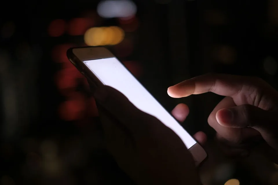 Fingerspitze tippt in einem dunklen Raum auf den hellen Bildschirm eines Smartphones während eines Browser-Vibrationschecks