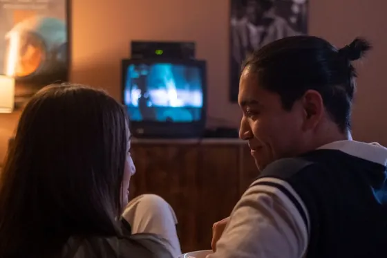 A couple on a couch in a dim home-theater room, the kind of 5.1 surround setup where rear speakers can end up playing through the front