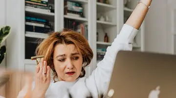 A person at a desk looking puzzled at a laptop while the spacebar is not working correctly