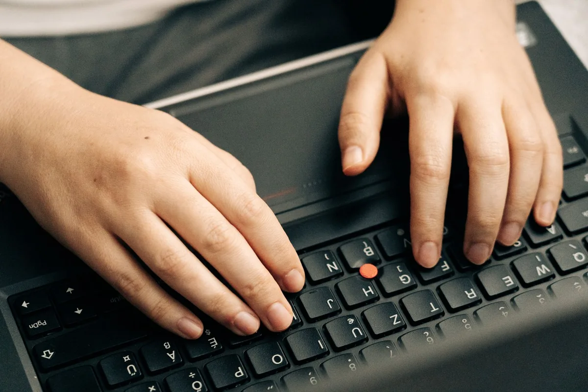 Close-up of hands pressing keys on a laptop keyboard during a live spacebar registration test