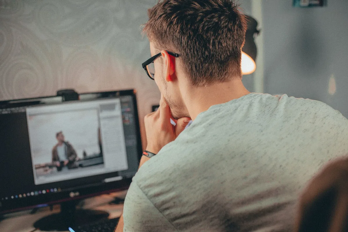 Seseorang fokus pada monitor desktop memeriksa ulang teks dan tepi setelah memperbaiki keburaman