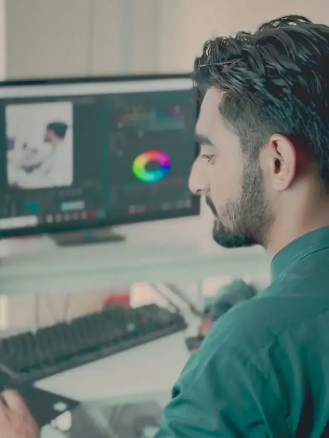 Man adjusting editing and color controls on two monitors