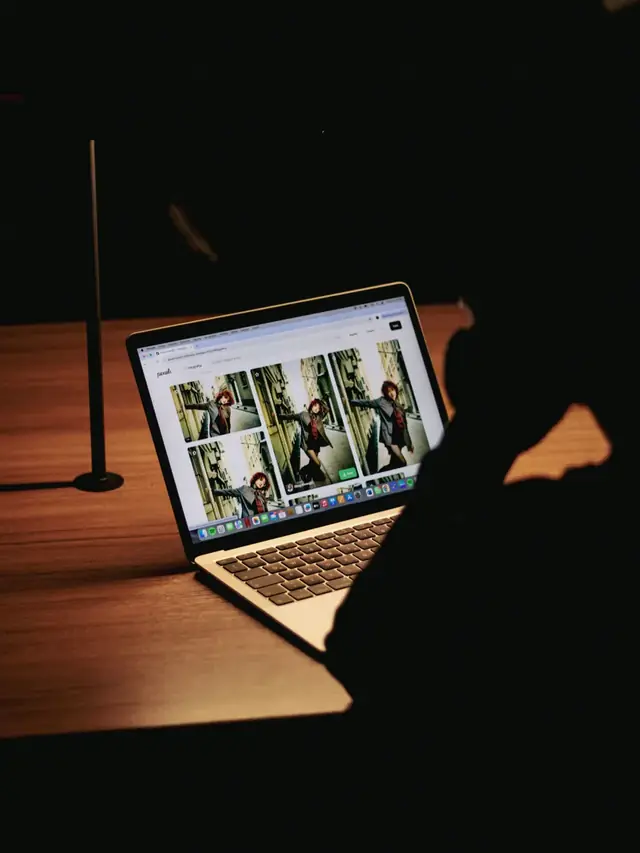 Person reviewing photographs on a laptop in a dark room