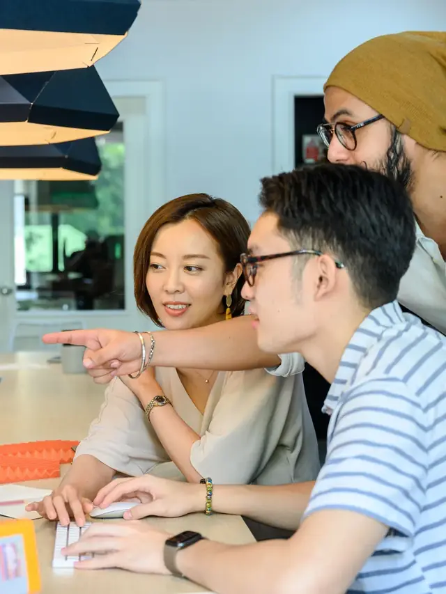 People closely examining and pointing at a computer monitor