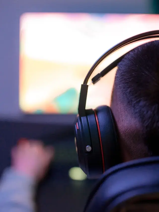 Person wearing headphones while viewing a colorful computer monitor