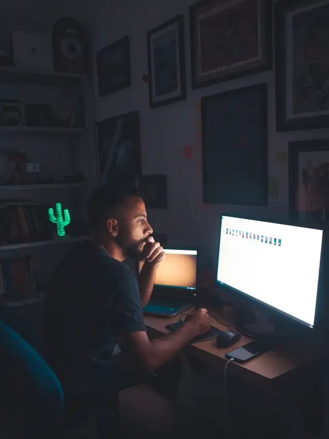 Pensive man examining images on a monitor in a dim room