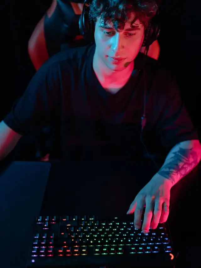 The recurring curly-haired gamer actively using a gaming keyboard from above; illustrative stock for a burst-fire setup