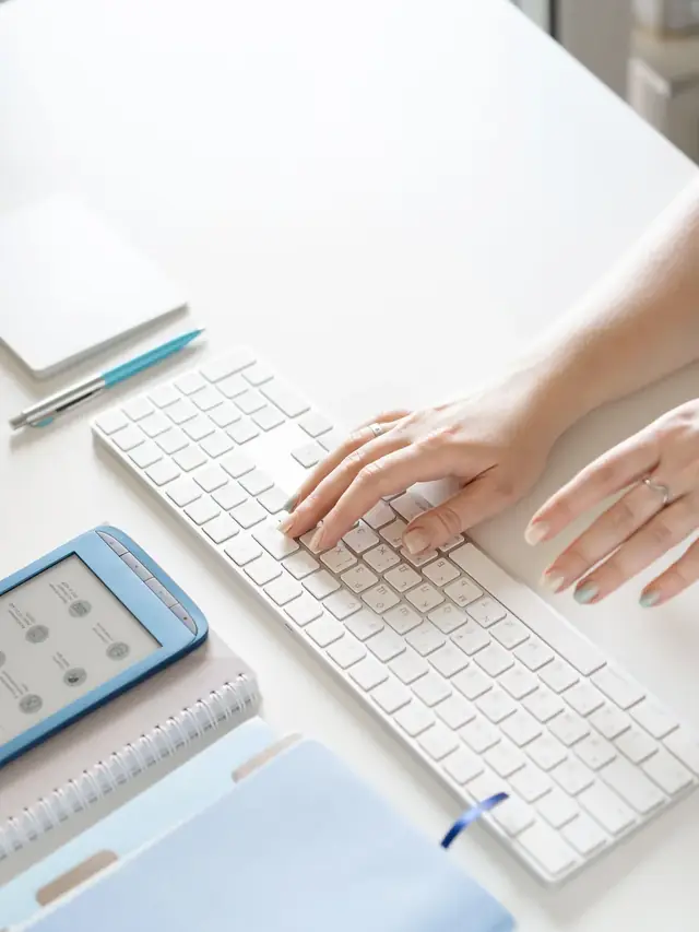 Hands typing on a bright white computer keyboard