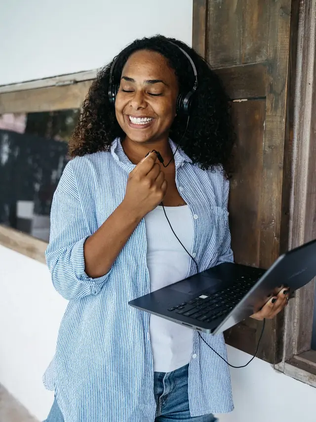 Relaxed woman wearing a headset while holding a laptop