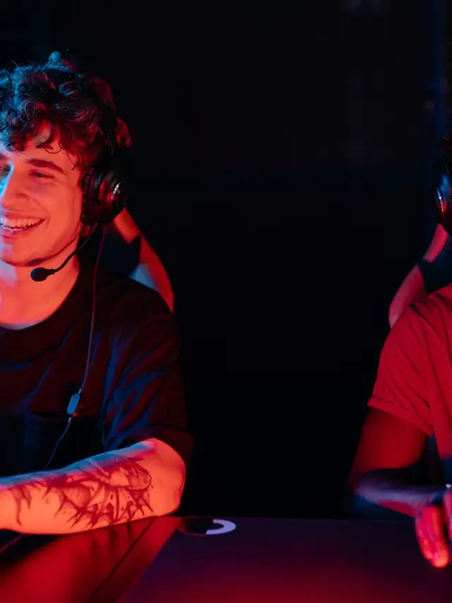 Two smiling gamers wearing headsets in colorful red and blue light