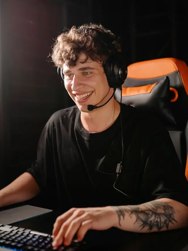 Smiling gamer wearing a headset while using a mechanical keyboard