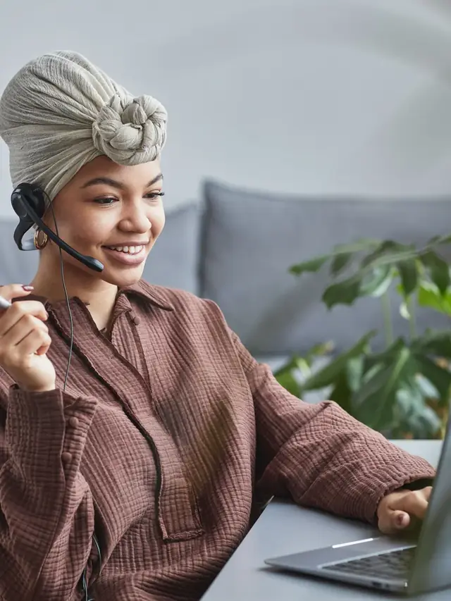 Smiling woman wearing a headset while working at a laptop